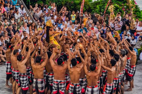 A group of men and women doing the Kecak fire dance in Bali, Indonesia wearing traditional clothes chequered black and white 