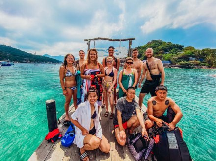 Group of people in swimwear standing on platform over blue ocean 